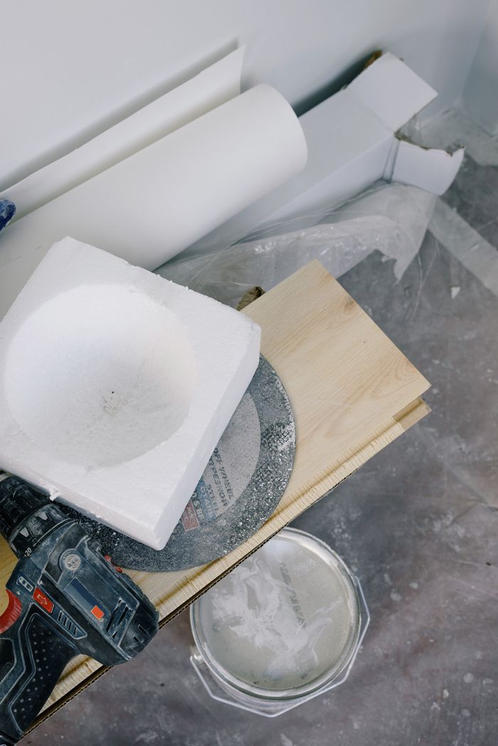 From above of bucket of white paint located under plywood plank with contemporary screwdriver and various materials for renovation